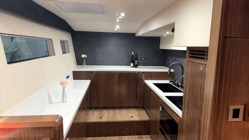  Yacht Photos Pics Luxurious kitchen interior of 2024 Mazarin 55 Catamaran Hybrid with modern wood finish.