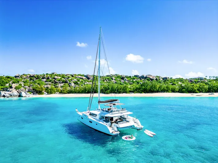  Yacht Photos Pics Fountaine Pajot Victoria 67 yacht anchored in turquoise waters near a tropical beach, 2017 model.