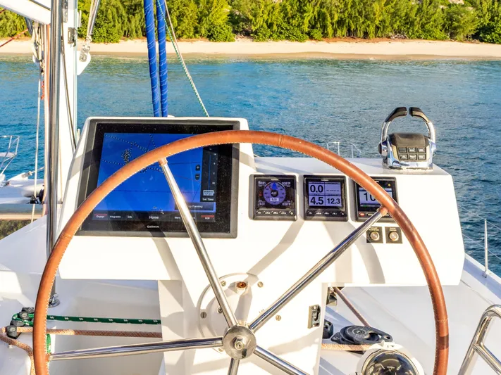  Yacht Photos Pics Steering wheel and navigation instruments on 2017 Fountaine Pajot Victoria 67 yacht, near a sandy beach.