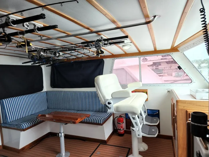 Ahi Ink Yacht Photos Pics 2003 Wesmac Flybridge interior with striped seating, fishing rods, and captain's chair.