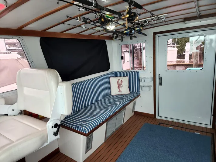 Ahi Ink Yacht Photos Pics 2003 Wesmac Flybridge interior with striped seating, fishing rods, and nautical decor.