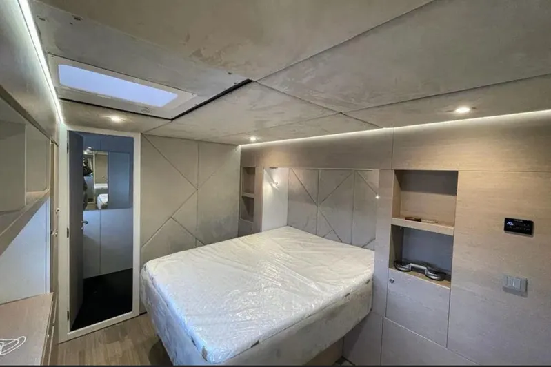  Yacht Photos Pics Modern CK70 2023 interior with bed, skylight, and built-in shelving.