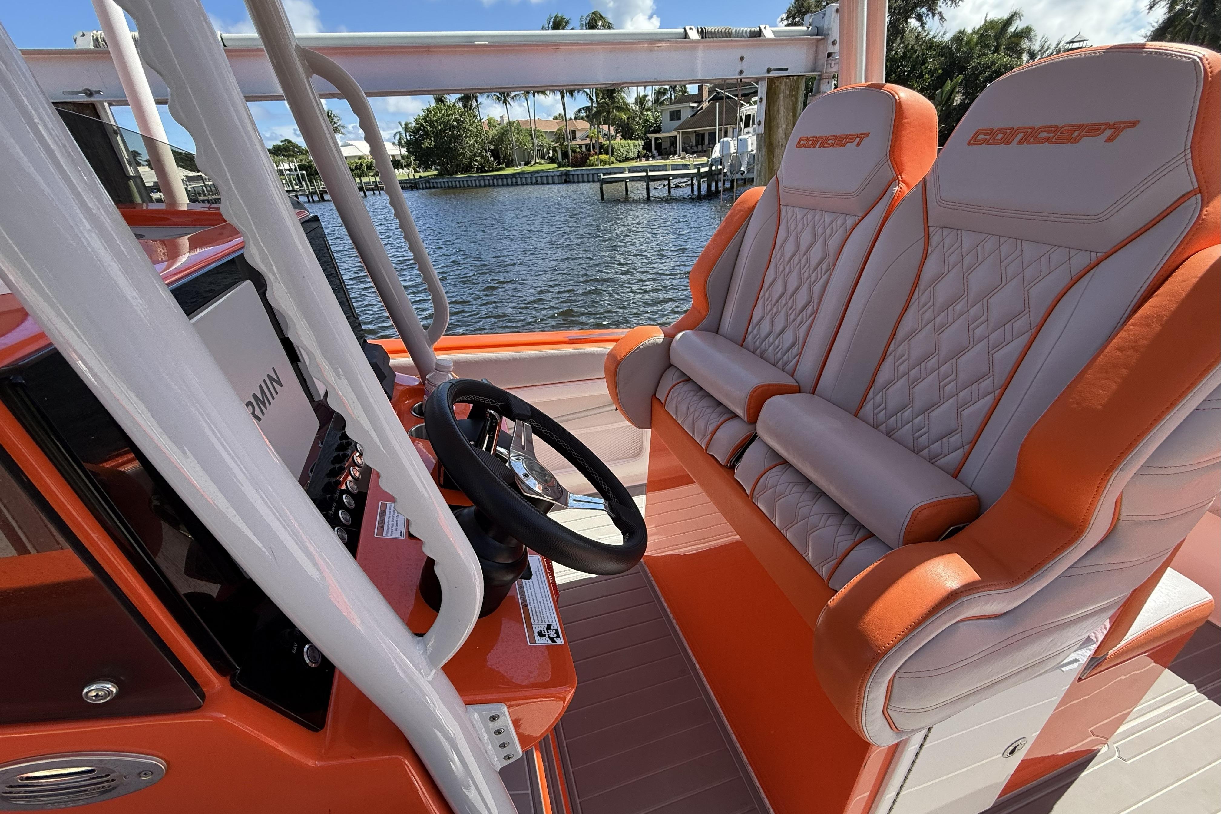 2025 Concept 32' CC boat interior with orange and white seating, steering wheel, and Garmin display.
