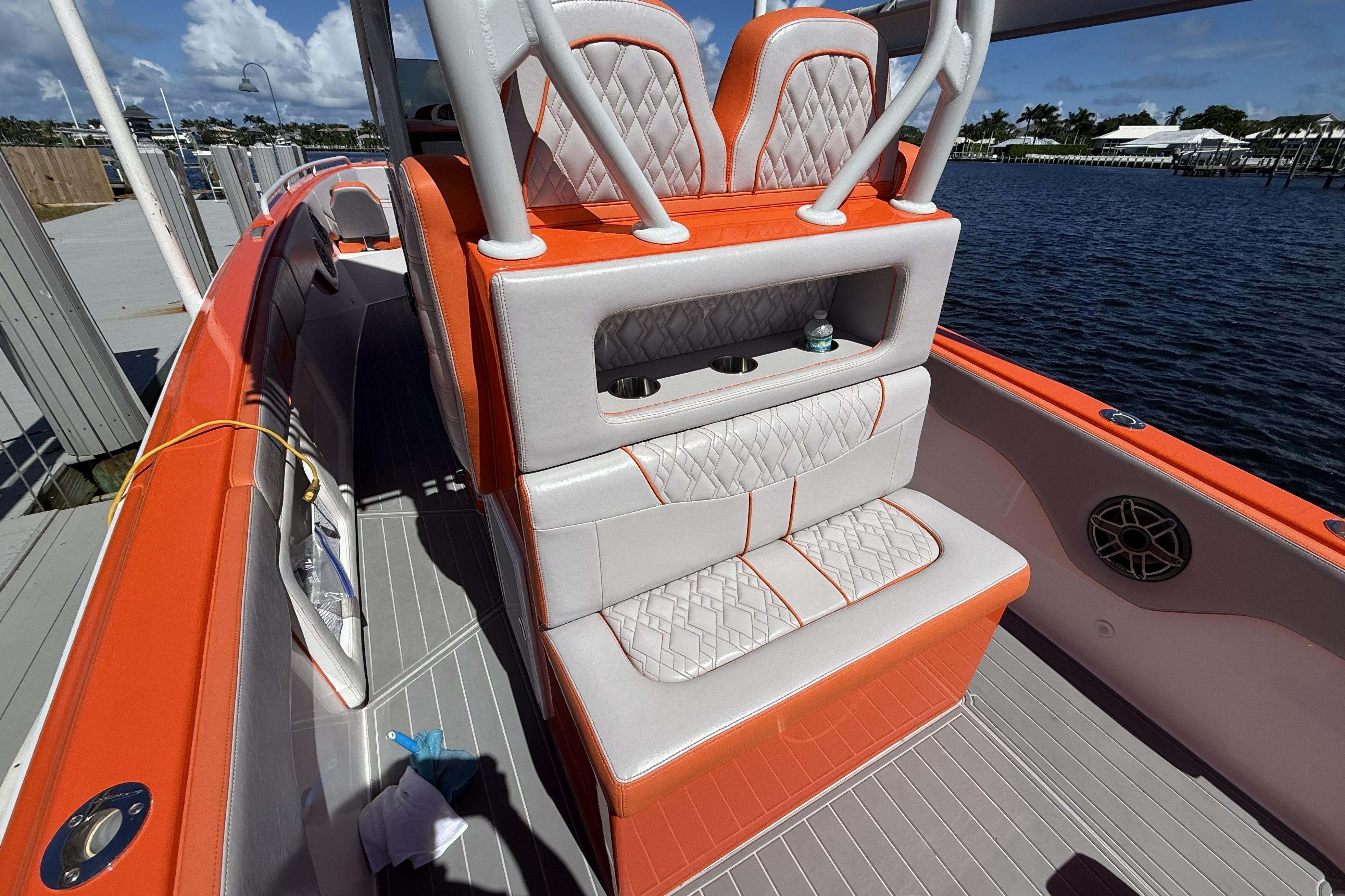 2025 Concept 32' CC boat with orange and white seating, docked by the water.