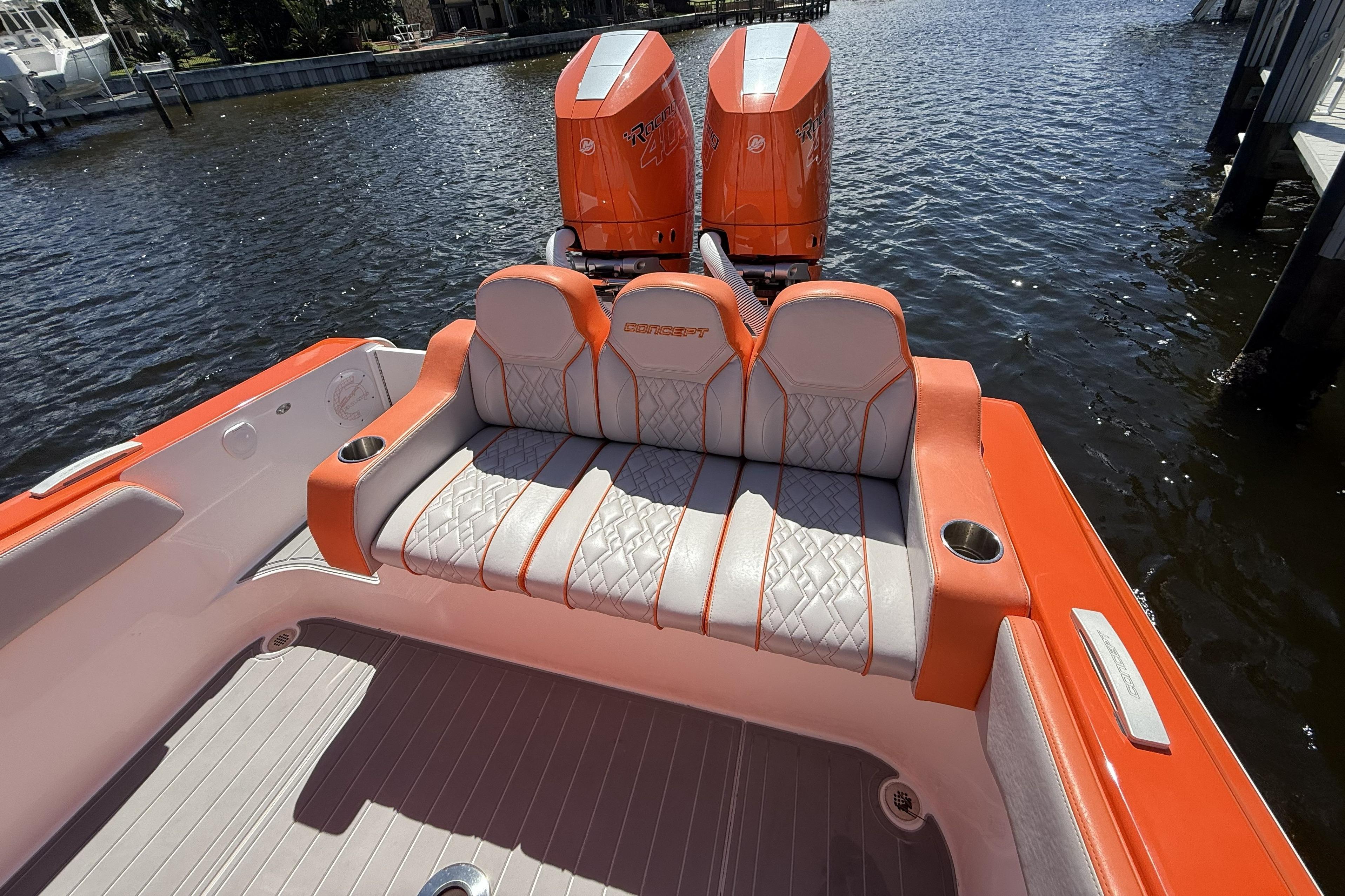 2025 Concept 32' CC boat with orange and white seating, dual engines, docked on water.