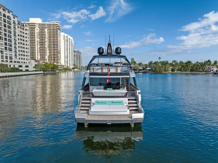 Beso Yacht Photos Pics 2024 Riva 102 Corsaro Super yacht on a serene waterway with cityscape backdrop.