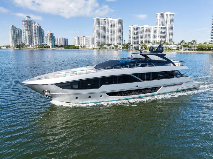 Beso Yacht Photos Pics 2024 Riva 102 Corsaro Super yacht cruising near modern city skyline.