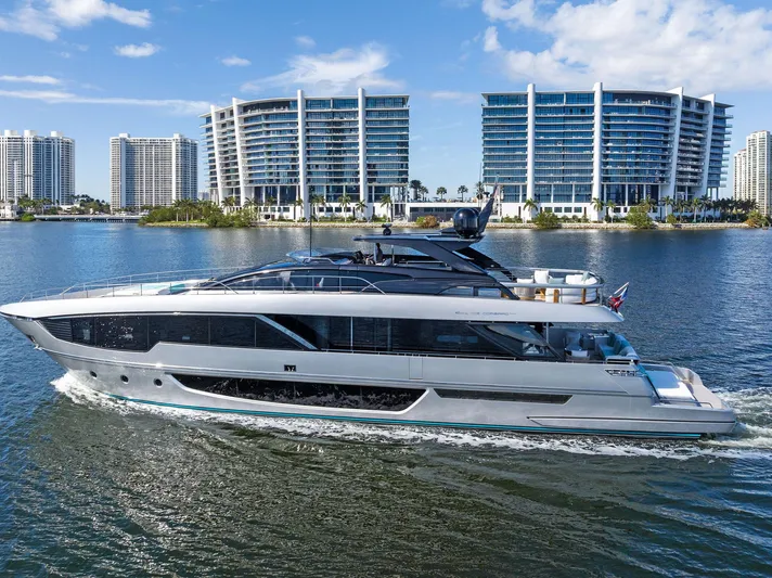 Beso Yacht Photos Pics 2024 Riva 102 Corsaro Super yacht cruising near modern waterfront buildings.