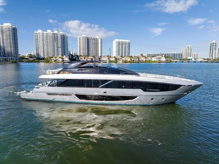 Beso Yacht Photos Pics Luxurious 2024 Riva 102 Corsaro Super yacht cruising near modern city skyline.