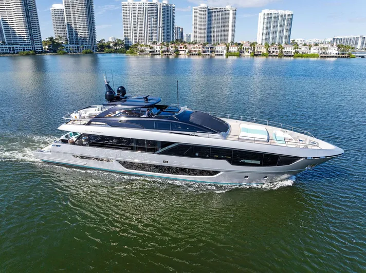 Beso Yacht Photos Pics 2024 Riva 102 Corsaro Super yacht cruising on a sunny day near city skyline.