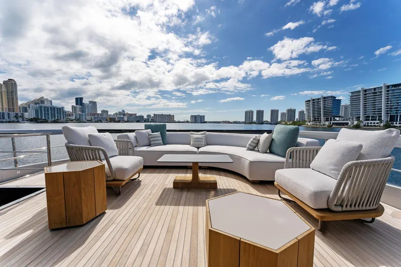 Beso Yacht Photos Pics Luxurious deck of 2024 Riva 102 Corsaro Super yacht with modern seating and city skyline view.