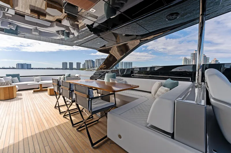 Beso Yacht Photos Pics Luxurious deck of 2024 Riva 102 Corsaro Super yacht with modern seating and city skyline view.