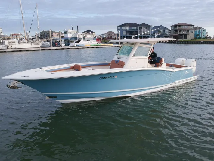 Knot Reel Serious Yacht Photos Pics 2015 Scout 320 LXF boat cruising in a marina with waterfront homes in the background.