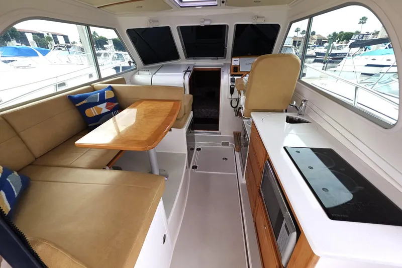 Jubilee Yacht Photos Pics 2018 Back Cove 32 interior with seating, table, and kitchenette in a marina setting.