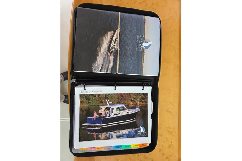Jubilee Yacht Photos Pics Open binder displaying 2018 Back Cove 32 boat brochures on a wooden table.