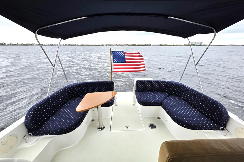 Jubilee Yacht Photos Pics 2018 Back Cove 32 boat with American flag, featuring cushioned seating and table on open water.