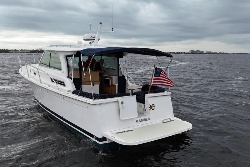 Jubilee Yacht Photos Pics 2018 Back Cove 32 boat cruising on water, American flag, overcast sky.