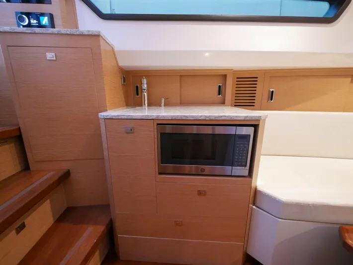 Low Hours Yacht Photos Pics 2020 Ocean Alexander 45 Divergence Sport interior with microwave and wooden cabinetry.
