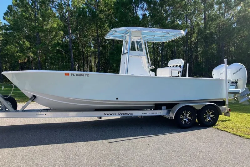  Yacht Photos Pics 2024 Latitude Tournament Boats 25 on trailer, parked outdoors with forest background.