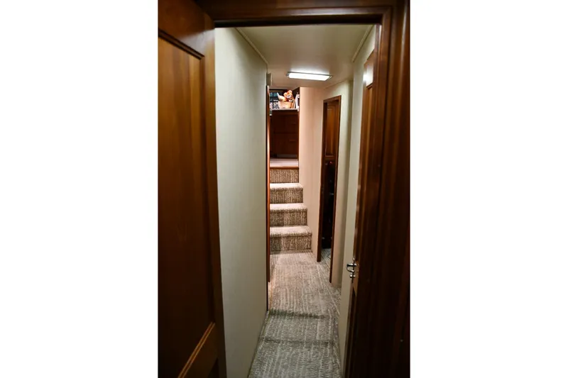Lay A Wake Yacht Photos Pics Interior hallway of 1990 Viking 53 Convertible yacht with carpeted stairs and wooden doors.