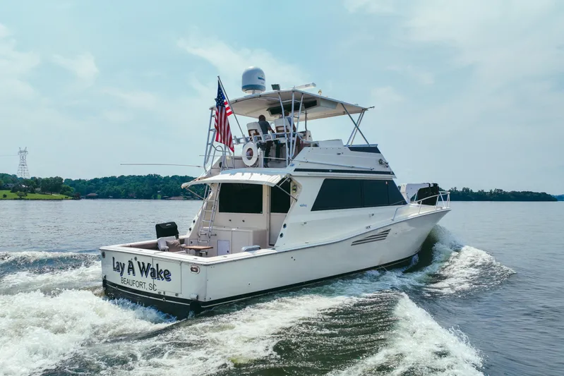 Lay A Wake Yacht Photos Pics 1990 Viking 53 Convertible yacht cruising on a lake with American flag.