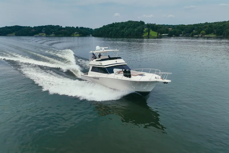 Lay A Wake Yacht Photos Pics 1990 Viking 53 Convertible yacht cruising on a serene lake with lush green shoreline.