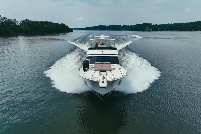 Lay A Wake Yacht Photos Pics 1990 Viking 53 Convertible yacht cruising on a serene lake, leaving a wake behind.