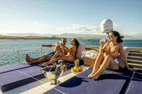 People relaxing on a yacht deck with drinks, enjoying a sunny day at sea.