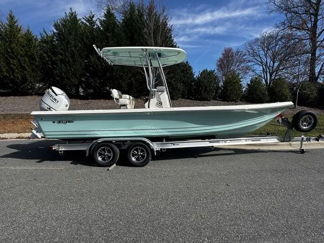 2025 Bulls Bay 2400 boat on trailer, parked on road, surrounded by trees.