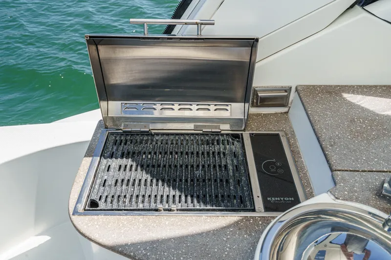 Cruel Summer Yacht Photos Pics Outdoor grill on 2012 Cruisers 380 Express yacht, set against a scenic water backdrop.