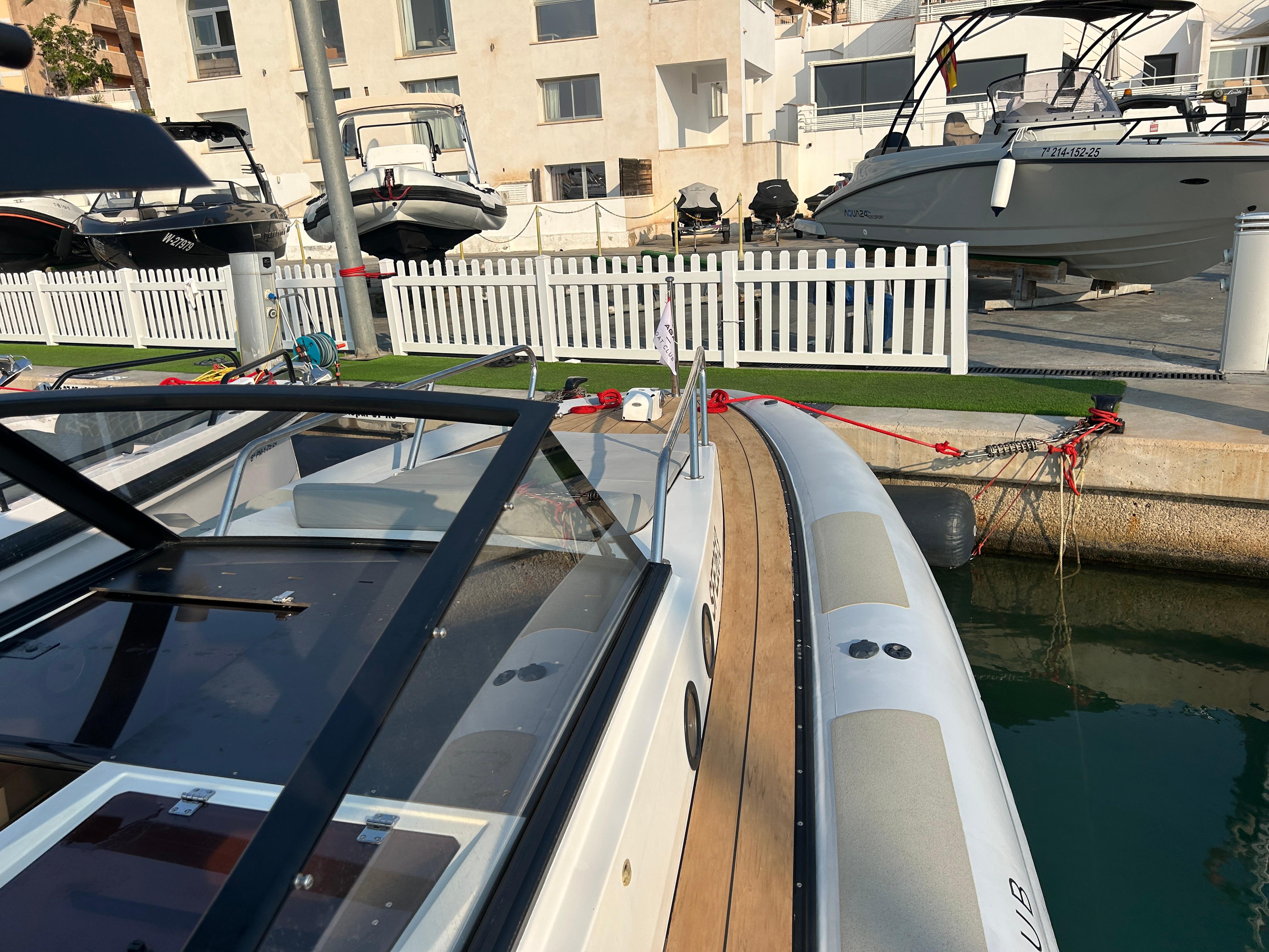 Agapi 950 boat docked at marina, 2017 model, with nearby vessels and white fence.