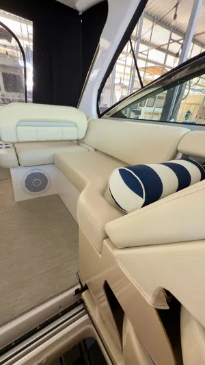  Yacht Photos Pics 2020 Regal 33 Express interior with beige seating and striped cushion in a boat showroom.
