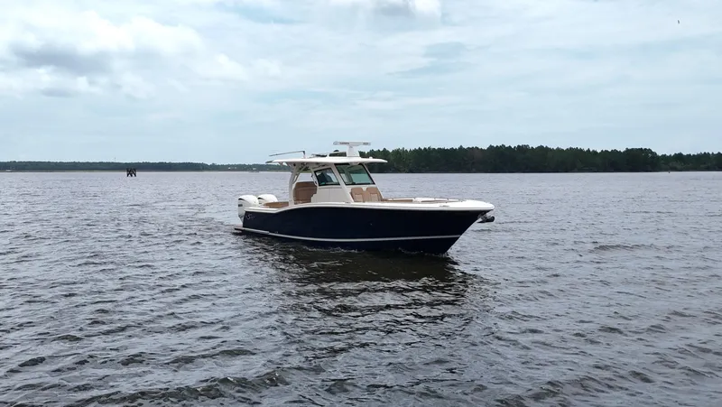 Engine Warranty X Trailer Yacht Photos Pics 2022 Scout 330 LXF boat on calm water under cloudy sky.