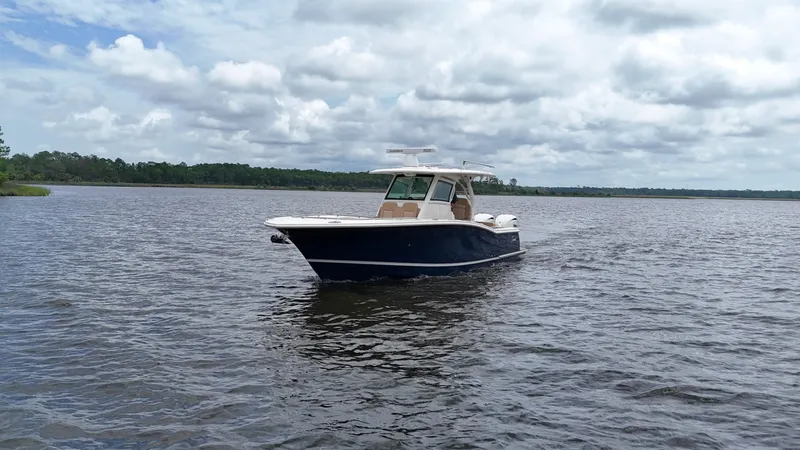 Engine Warranty X Trailer Yacht Photos Pics 2022 Scout 330 LXF boat on a calm lake under cloudy skies.