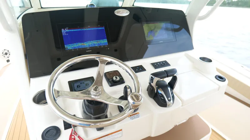 Engine Warranty X Trailer Yacht Photos Pics 2022 Scout 330 LXF boat dashboard with steering wheel and navigation screens.