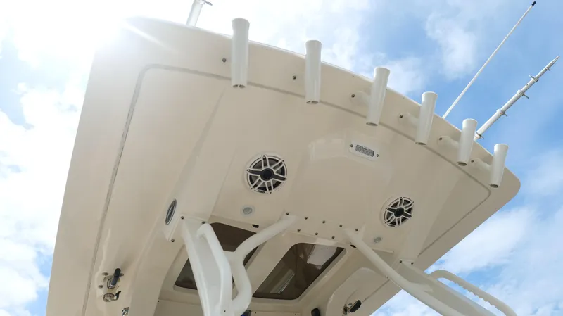 Engine Warranty X Trailer Yacht Photos Pics 2022 Scout 330 LXF boat roof with rod holders and speakers against blue sky.