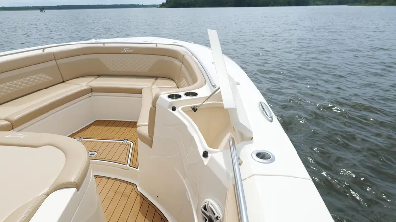 Engine Warranty X Trailer Yacht Photos Pics 2022 Scout 330 LXF boat interior with tan seating and open storage on a calm lake.