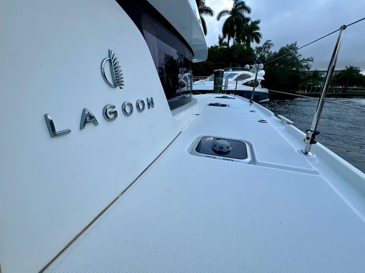 Orion Yacht Photos Pics 2019 Lagoon 42 catamaran deck with logo, docked near palm trees.