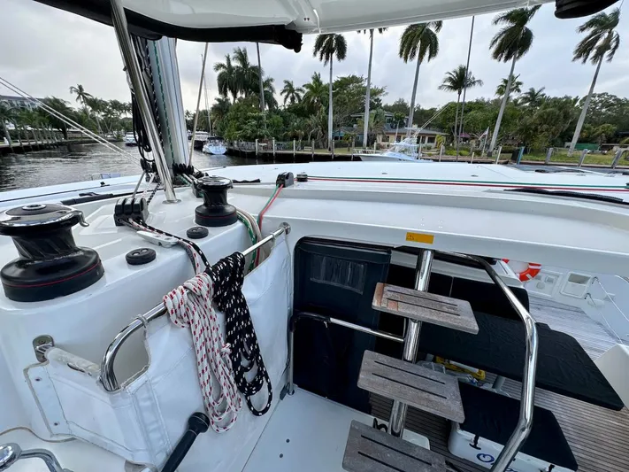 Orion Yacht Photos Pics 2019 Lagoon 42 yacht deck with ropes and winches, docked near palm trees.