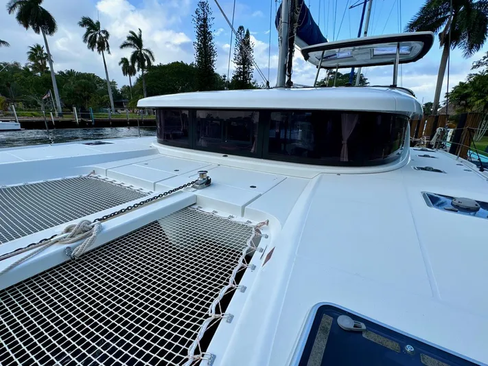 Orion Yacht Photos Pics 2019 Lagoon 42 catamaran deck with netting, docked near palm trees.