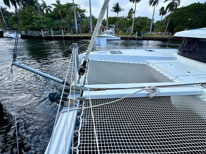 Orion Yacht Photos Pics 2019 Lagoon 42 catamaran docked by palm trees, featuring netted deck area.