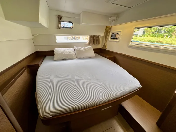Orion Yacht Photos Pics Interior cabin of a 2019 Lagoon 42 catamaran with a cozy bed and windows.