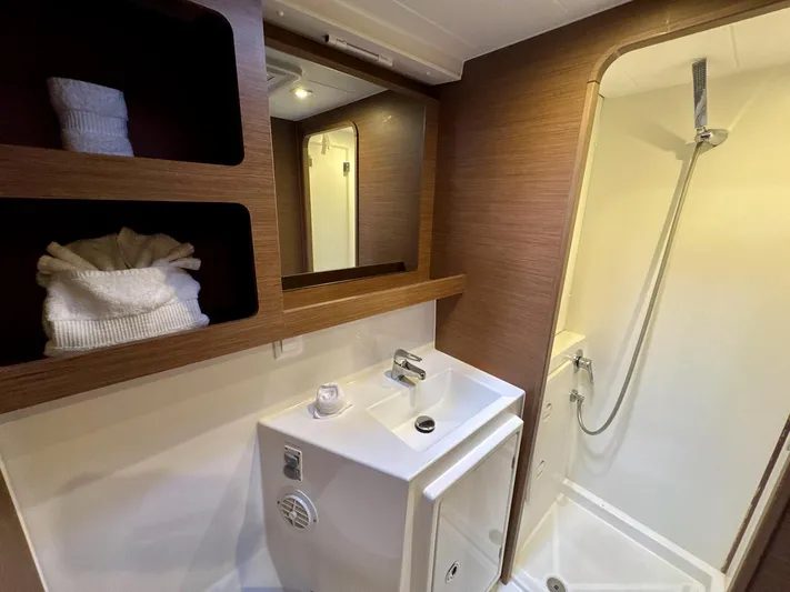 Orion Yacht Photos Pics Bathroom interior of 2019 Lagoon 42 yacht with sink, shower, and wooden shelving.