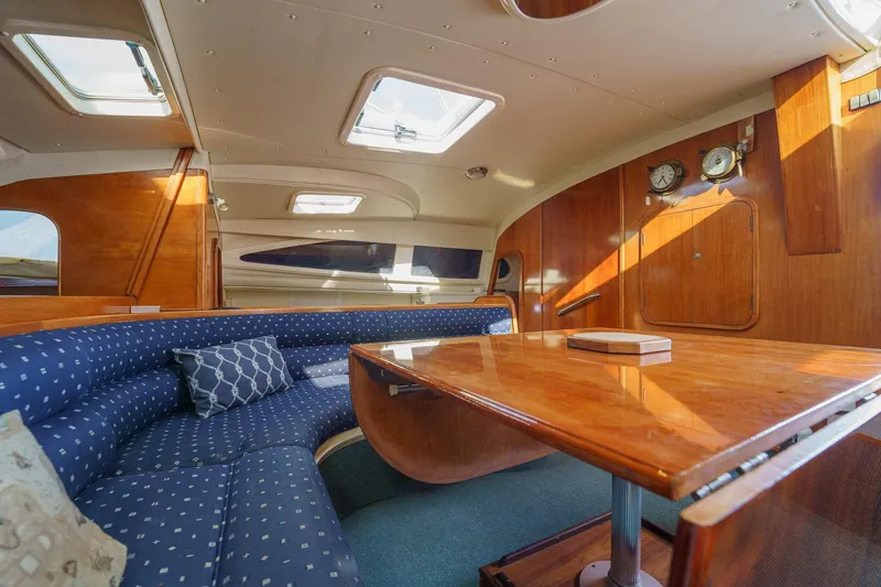 Solitude Yacht Photos Pics Interior of 1995 Prout 45 yacht with wooden table and blue cushioned seating.
