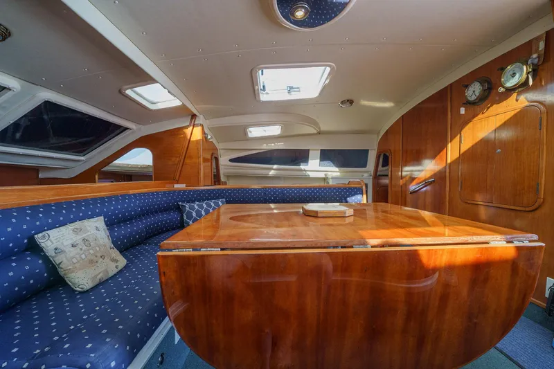 Solitude Yacht Photos Pics Interior of 1995 Prout 45 yacht with wooden table and blue cushioned seating.