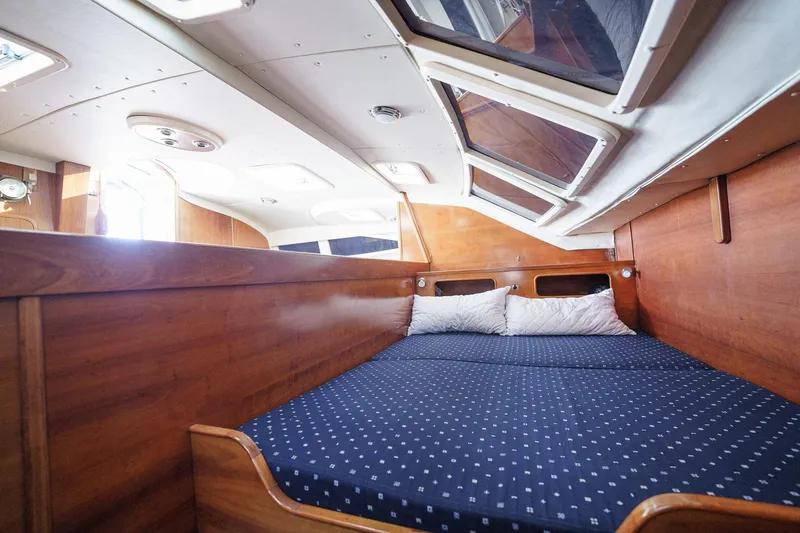 Solitude Yacht Photos Pics Cozy cabin interior of 1995 Prout 45 yacht with wooden finish and blue bedding.