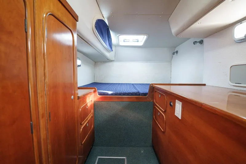 Solitude Yacht Photos Pics Interior cabin of a 1995 Prout 45 yacht with wooden cabinetry and a cozy bed.