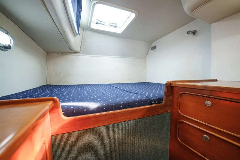 Solitude Yacht Photos Pics Cozy cabin interior of a 1995 Prout 45 yacht with a comfortable bed and wooden storage.