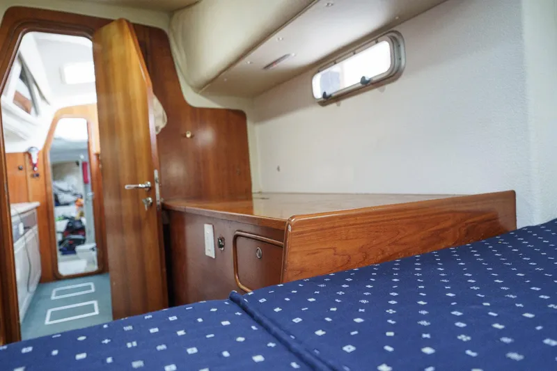 Solitude Yacht Photos Pics Interior cabin of a 1995 Prout 45 yacht with wooden furnishings and blue bedding.
