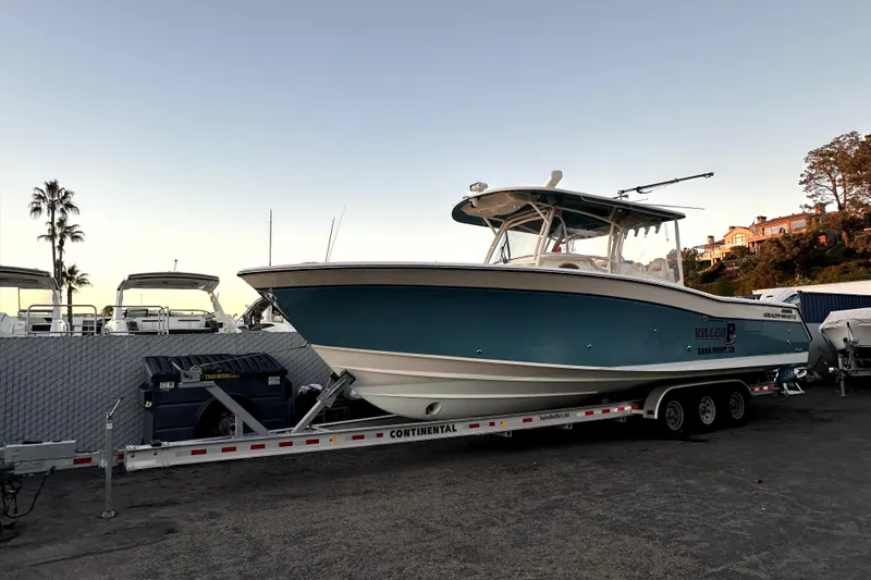 Killer B Yacht Photos Pics 2019 Grady-White Canyon 336 boat on trailer at sunset, parked near palm trees.